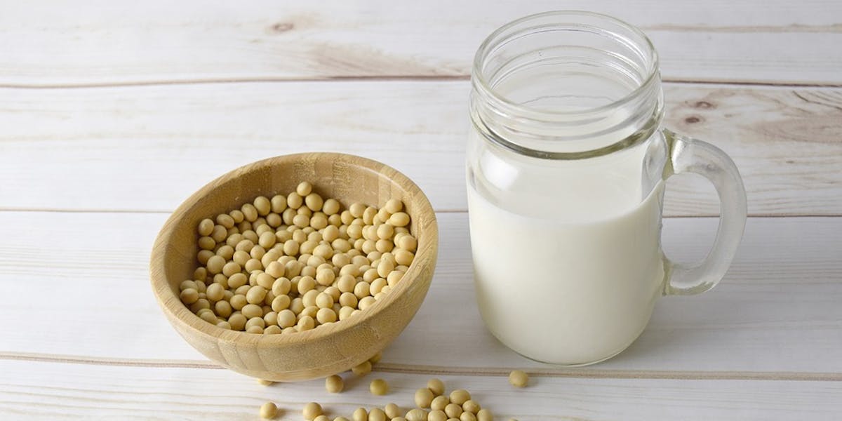 Bowl of raw soy beans and glass of soy milk