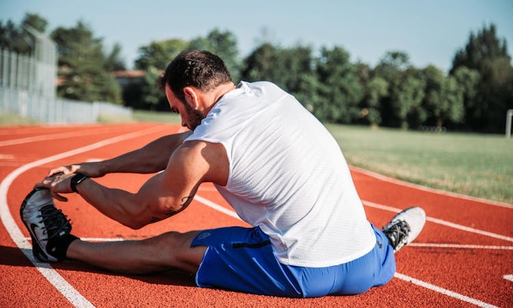 man stretching on an athletic track