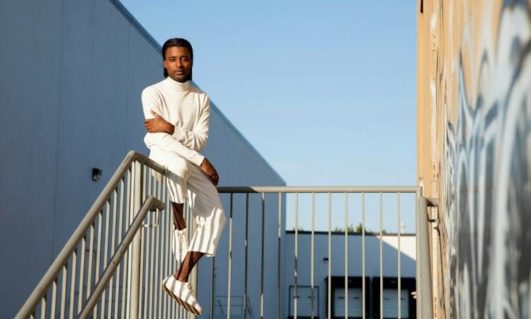 male model sitting on a railing in the sun