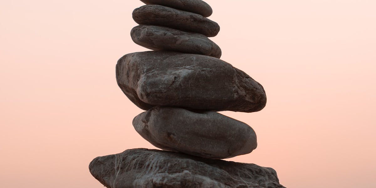 balancing stones in front of a sun set