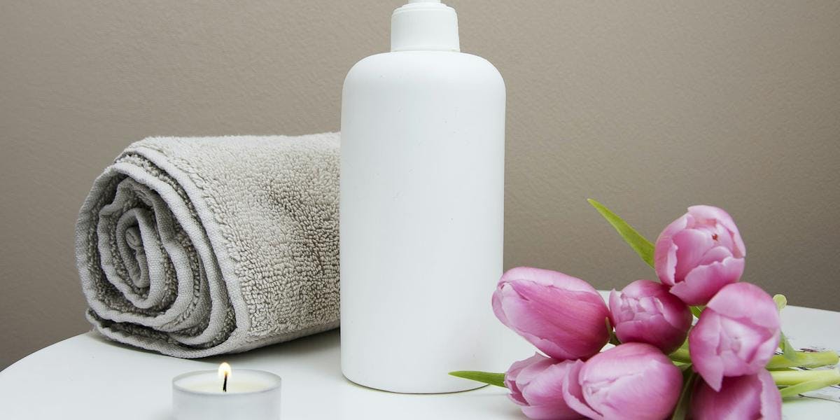 bottle of lotion next to flowers and a towel