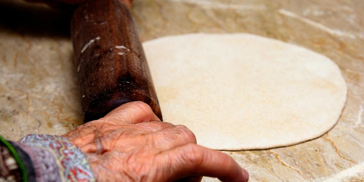 person rolling out dough for naan