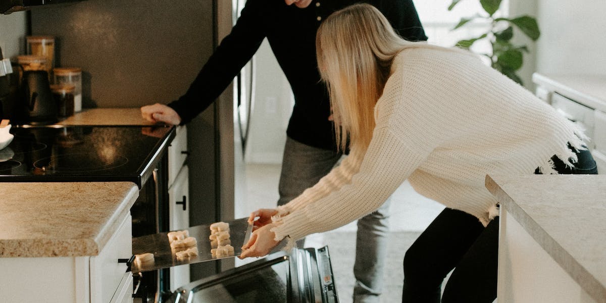 two people putting food in the oven