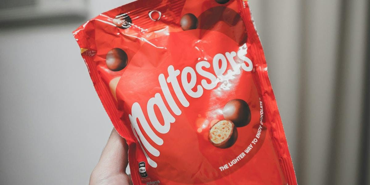 a hand holding a packet of Maltesers