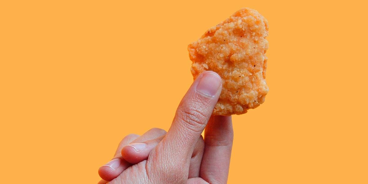 a hand holding a vegan nugget