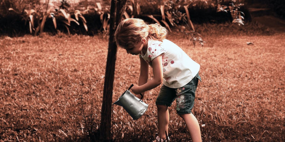 little girl watering a tree