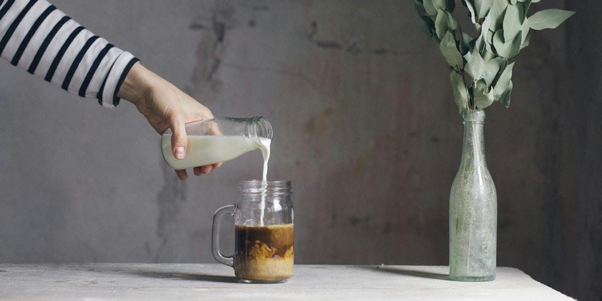 person pouring milk into coffee
