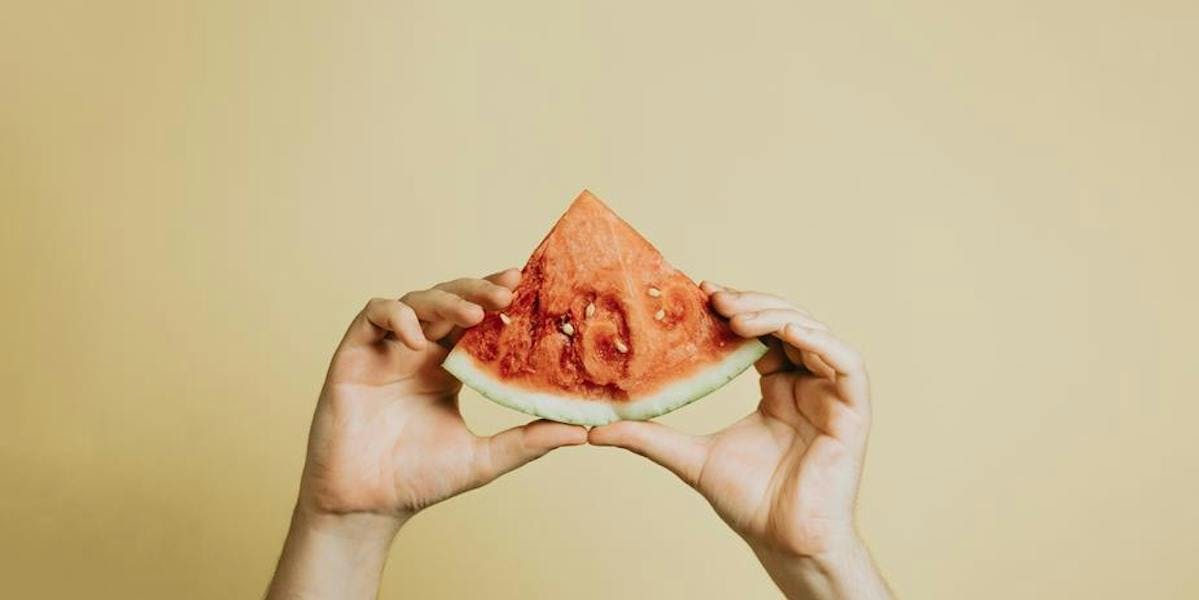 hands holding up a slice of watermelon