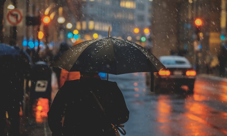 someone walking through a city with an umbrella 