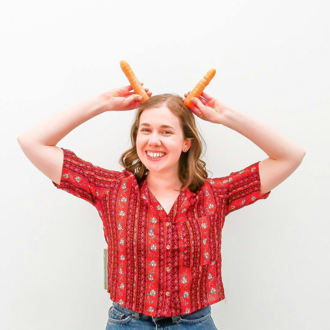 person holding carrots to their head like antlers 