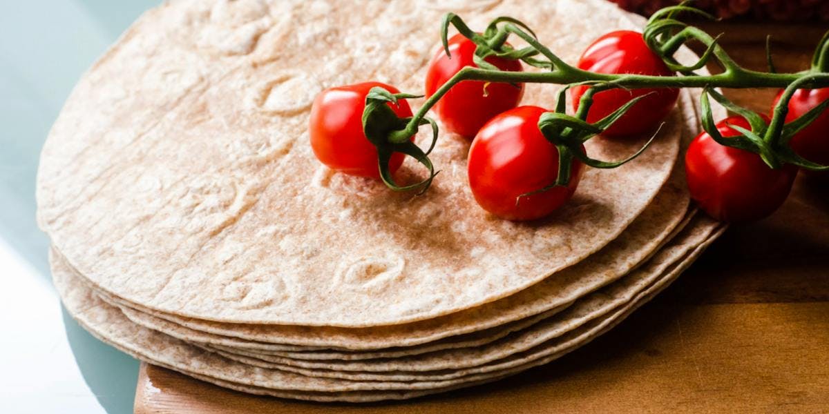 a stack of tortilla wraps with tomatoes on top