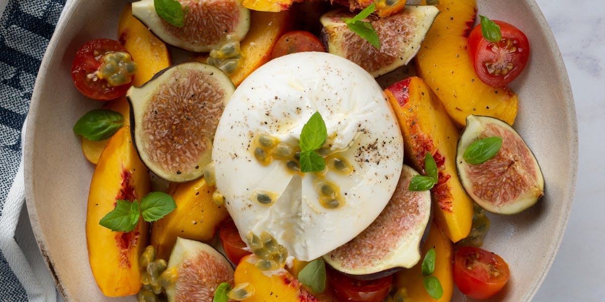 a ball of burrata on top of nectarines and figs