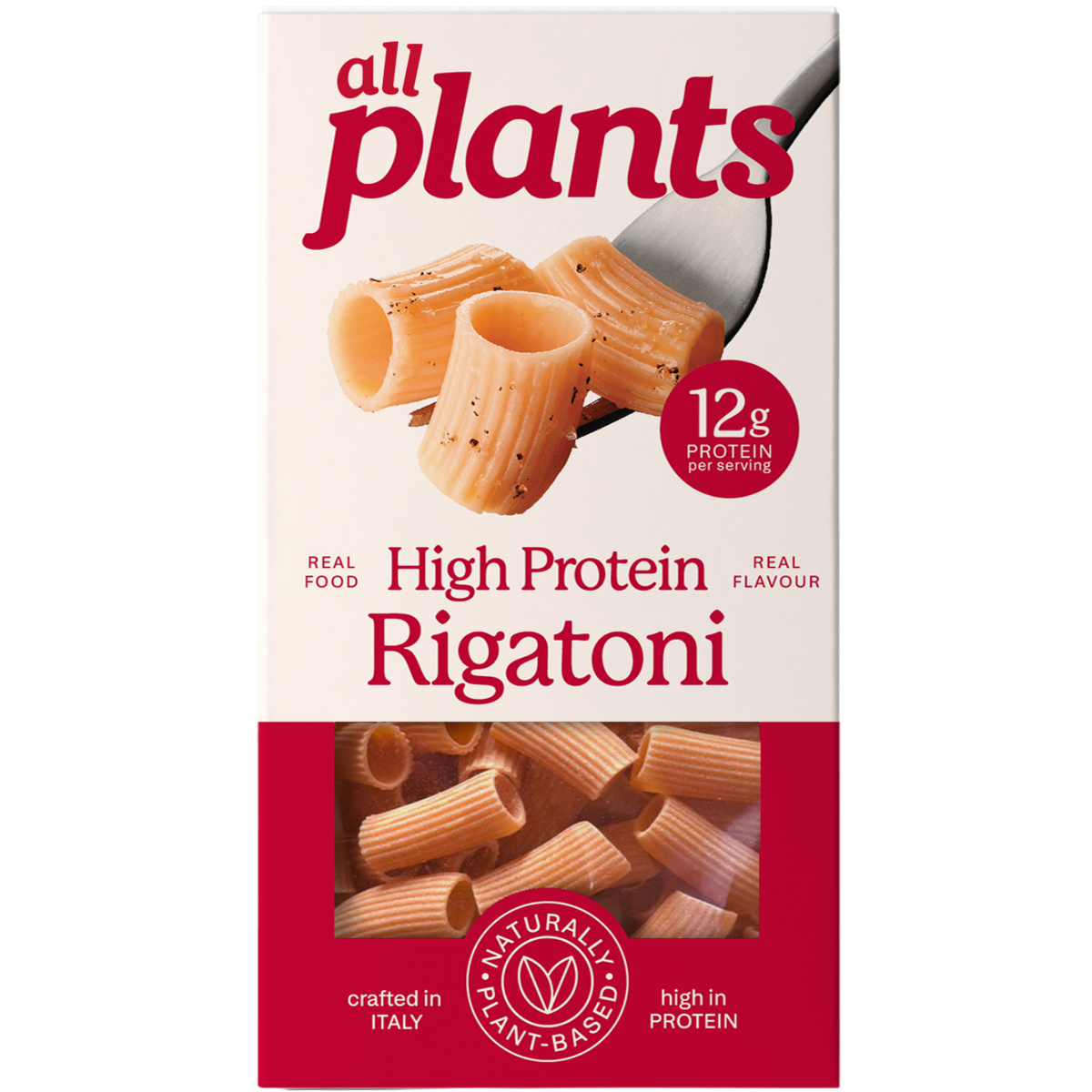 A package of All Plants High Protein Rigatoni pasta on a plain white background. The box is cream-colored on the top half with red branding and pasta imagery, and dark red on the bottom half showing the pasta through a window.